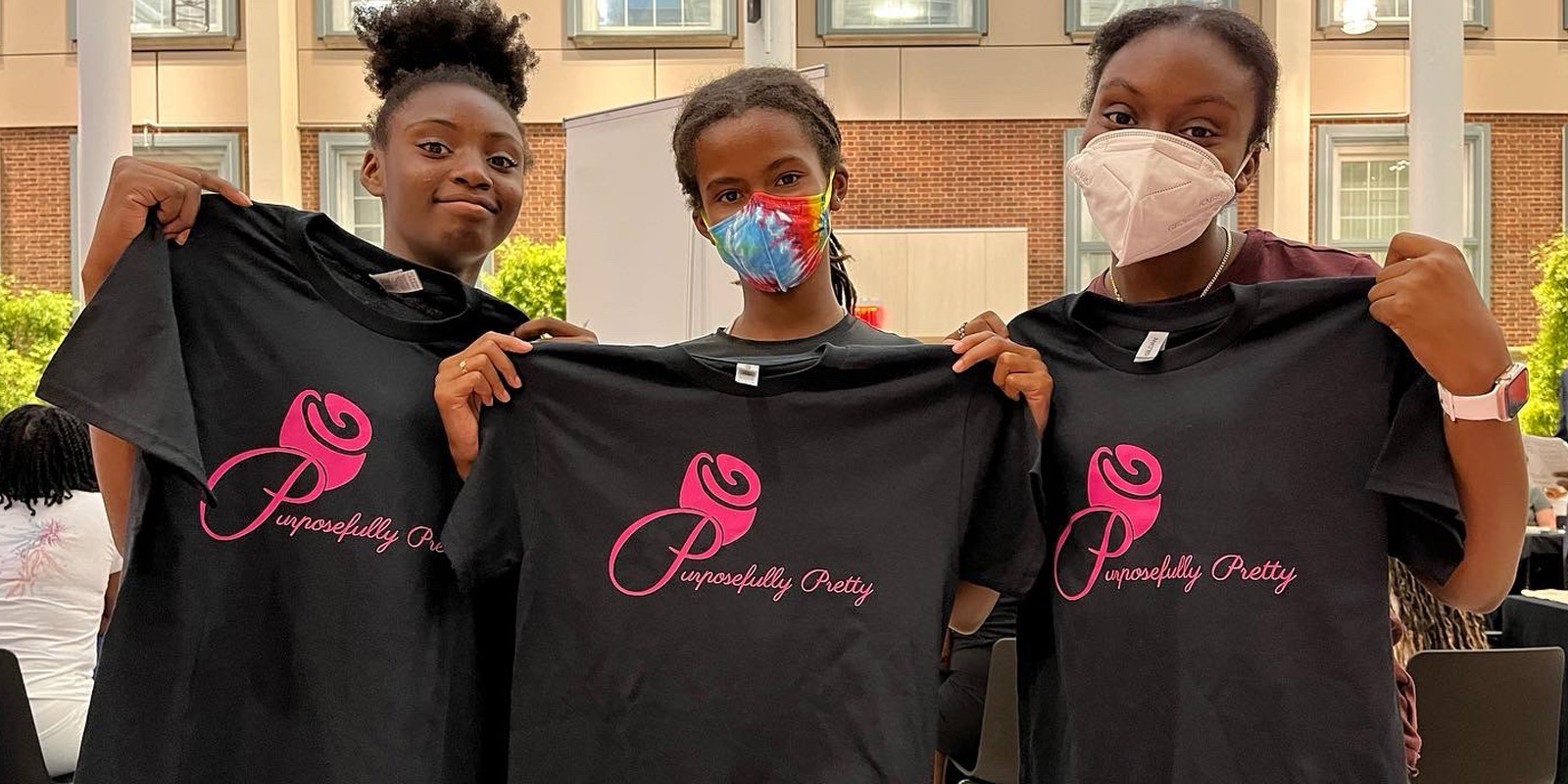 Three girls holding t shirts